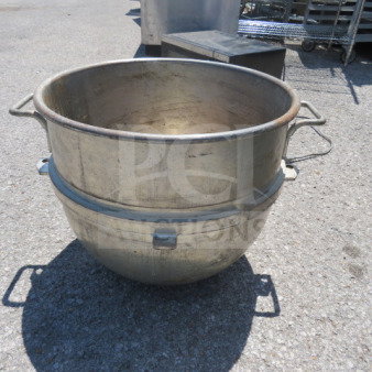 Stainless steel mixing bowl, large, with side handles, visible wear, suitable for commercial kitchen use.