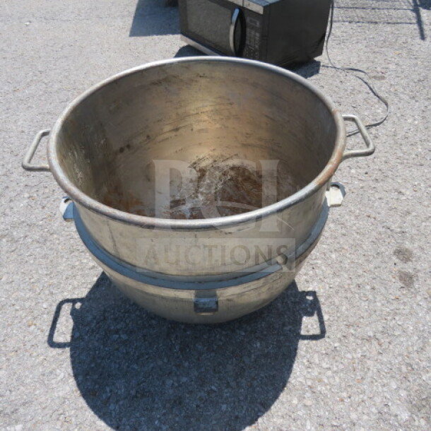 Large stainless steel mixing bowl with side handles, showing signs of wear and surface rust at the base.