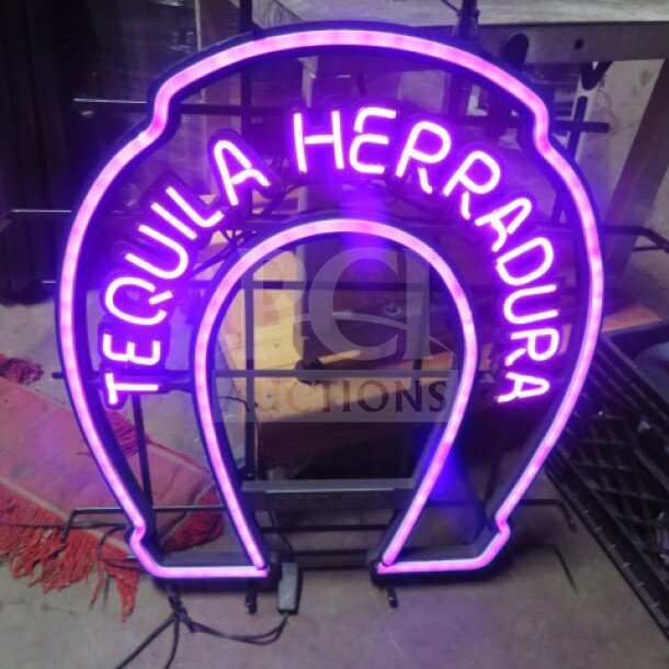 Neon Herradura Tequila electric sign in pink and purple, horseshoe shape, working condition, with visible power cord.