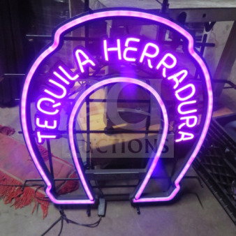 Neon Herradura Tequila electric sign in pink and purple, horseshoe shape, working condition, with visible power cord.
