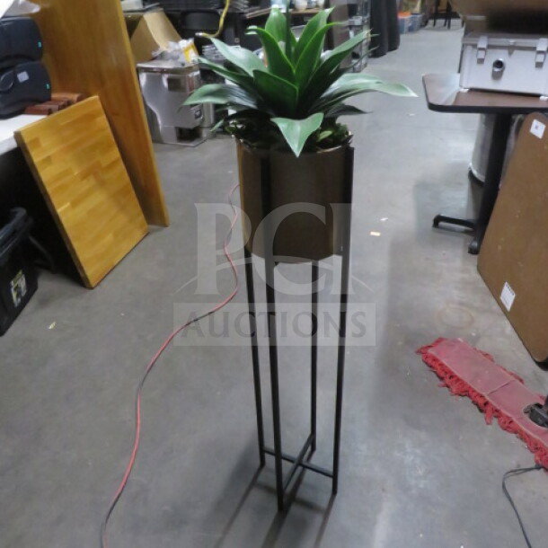 A potted plant in a tall, sleek metal stand, featuring vibrant green leaves. Suitable for modern decor.