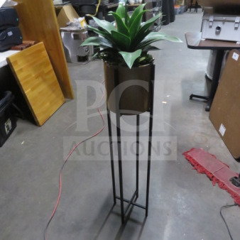 A potted plant in a tall, sleek metal stand, featuring vibrant green leaves. Suitable for modern decor.