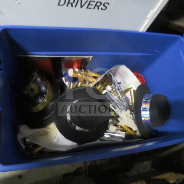 Large blue bin containing assorted decorative items, including black hats, shiny decor, and various metallic pieces.