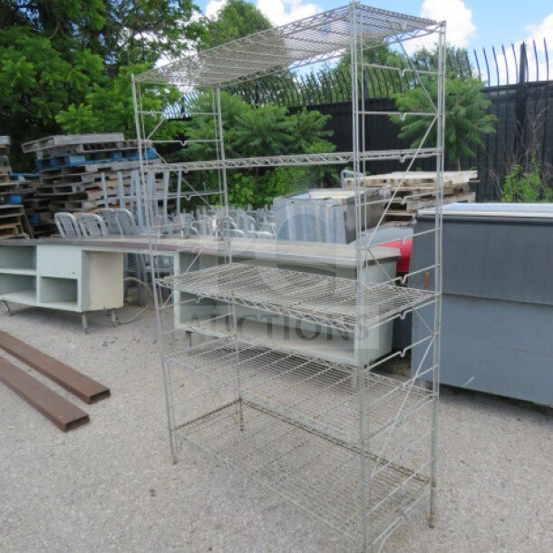 Metal shelving unit with 5 wire shelves, measuring 48x18x73 inches. Outdoor setting, sturdy construction, used condition.