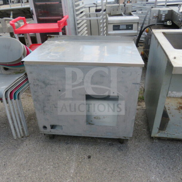 Industrial worktop table, metal, 34x24x35 inches, on wheels. Worn surface; suitable for kitchen or workshop use.