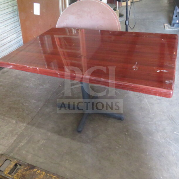 Wooden table with glossy finish, 48x30x30 inches. Features a sturdy black pedestal base. Some surface wear visible.