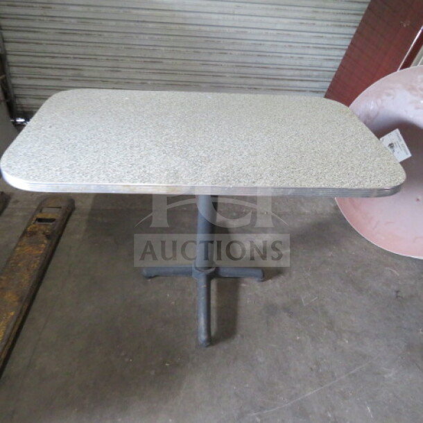 Laminate table on pedestal base, dimensions 48x30x30 inches, speckled surface, metal base, used condition.