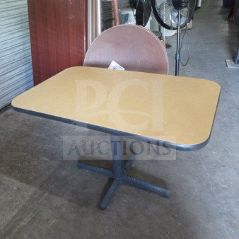 Laminate table with pedestal base, 42x26x30 inches. Tan top, black trim. Good condition. Ideal for office or dining use.