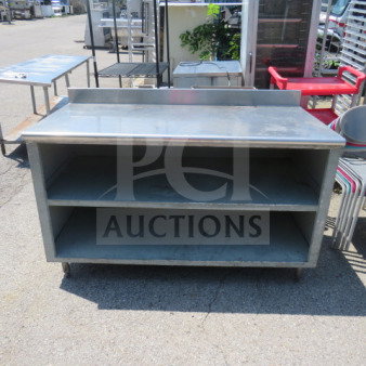 Stainless steel work table, 60x30x39 inches, with 2 shelves. Includes rear backsplash. Used condition, visible wear.