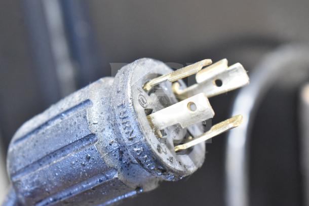 Close-up of the power plug for a 2019 True GDM-72F-HC commercial freezer, showing metal prongs and a textured cap.