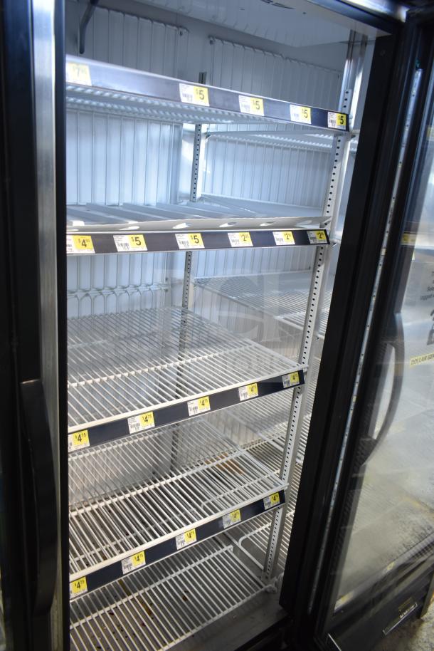 2019 True GDM-72F-HC 3-door commercial freezer with glass doors, adjustable shelves, and visible pricing labels inside.