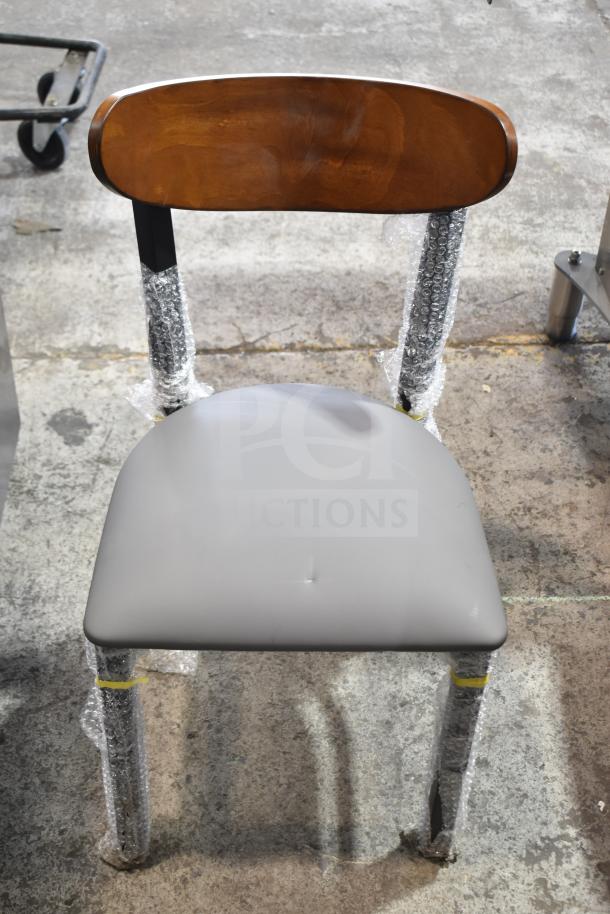 Brand new Lancaster Table & Seating dining chair, model 164CBMRGBFRN, with wooden back, gray seat, and metal frame.