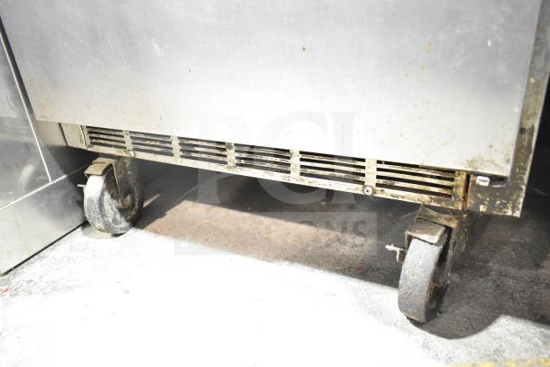 Beverage Air SPE27-B sandwich prep table on worn commercial casters, showing lower vent and stainless steel surface.