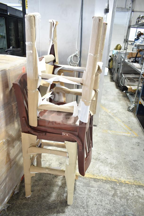 Two brand new wooden bar height chairs, scratch and dent, partially wrapped for protection, in a storage area.