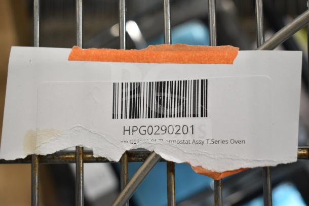 Barcoded tag with code "HPG0290201" and text "Thermostat Assy T. Series Oven," taped to a metal grid.