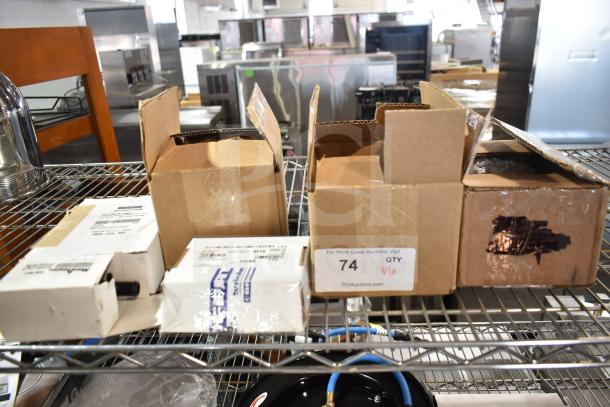 Boxes containing brand new scratch and dent items: oil pump, float switch, ignition module. Auction tag reads "74 QTY."