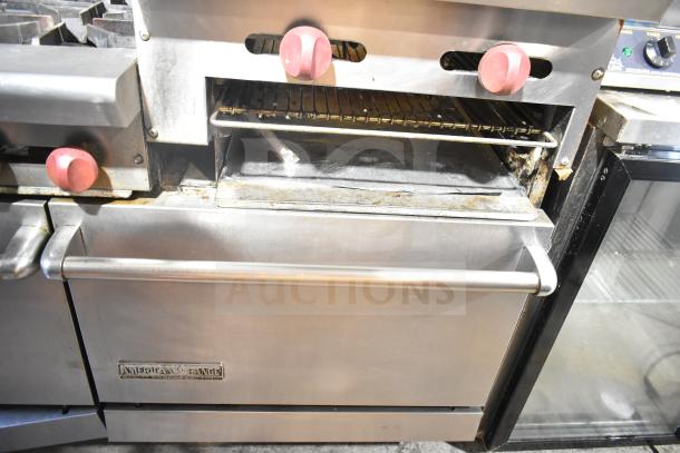 American Range commercial 6-burner range with flat top, two ovens, over shelf, backsplash. Used condition. Visible branding on oven door.