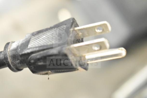 Close-up of a power plug from a Furman M-8Lx Power Conditioner, showing its metal prongs, slight wear evident.