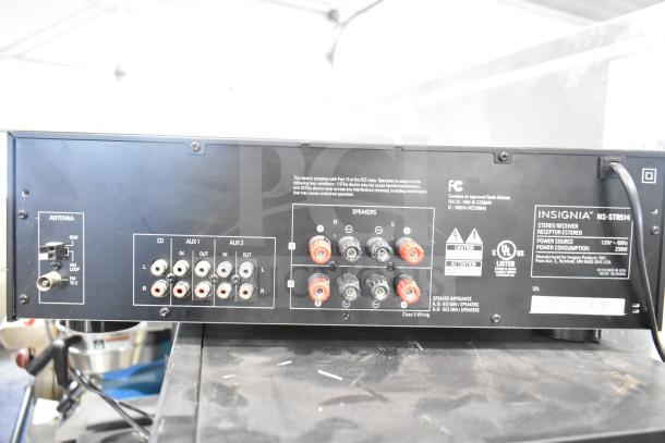 Back panel of Insignia NS-STR514 stereo receiver showing multiple inputs for CD, AUX, antenna connections, and speaker outputs. Labels indicate power specifications and compliance codes.