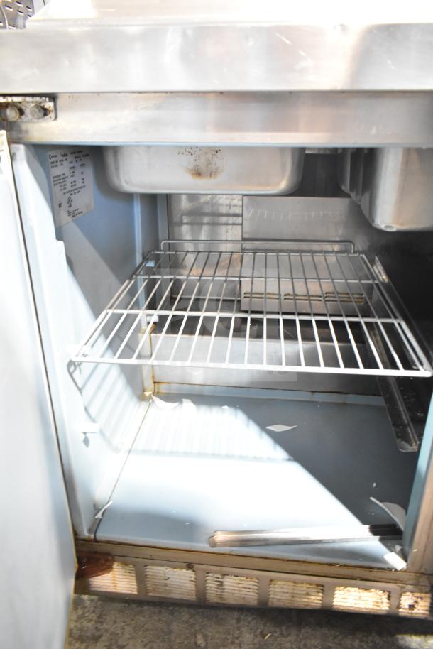 Delfield 4472N-18M prep table interior with shelves and label. 115V, 1-phase. Visible wear suggests usage.