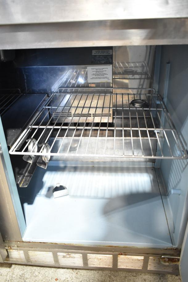 Delfield 4472N-18M sandwich salad prep table interior, showing wire shelves and stainless steel surfaces, used condition.