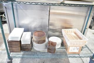 Tiered shelf with various kitchen items, including stacks of rectangular plates, round plates, and wicker baskets.