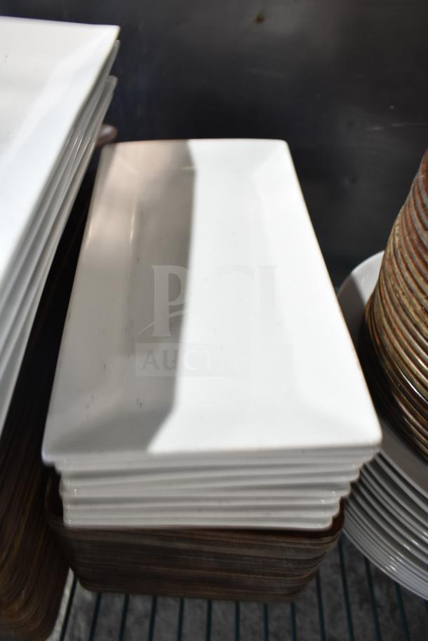 Stack of rectangular white plates, varied condition, part of an auction tier lot with baskets and other items.