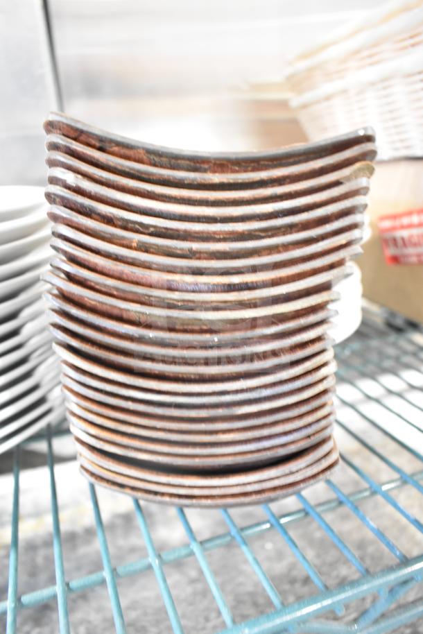 Stack of rectangular brown plates on a metal rack, part of a mixed auction lot including baskets. Plates appear gently used.