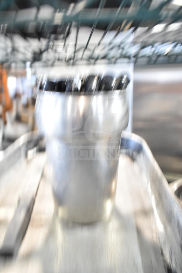 Blurry image of kitchenware lot, including stainless steel bins and other cooking items on a shelf.