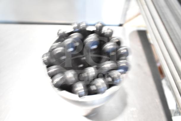 Blurry image of bundled kitchen utensils, including possible knives and stainless steel components.
