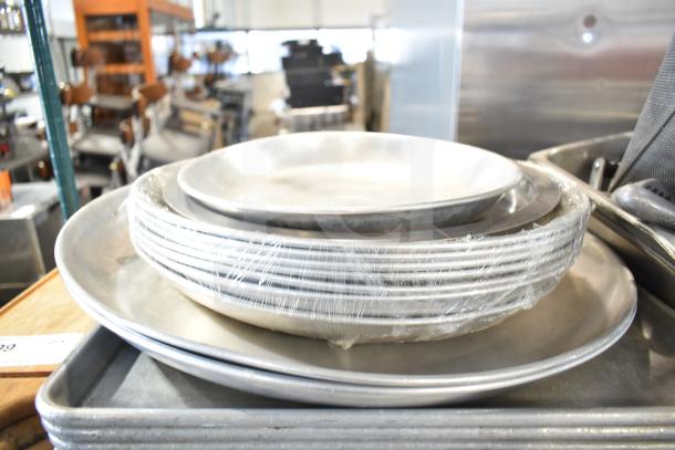 A stack of metal baking pans, wrapped in plastic, part of a varied auction lot.