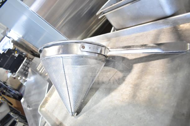 Alt Text: Stainless steel china cap strainer with handle, part of a kitchenware tier lot, on metal surface.