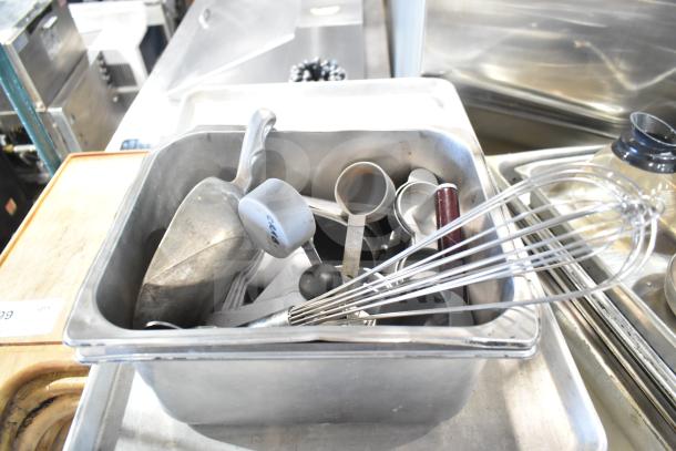 Auction lot with baking pans, stainless steel bins, China cap strainer, stock pot, cutting boards, and knives in used condition.