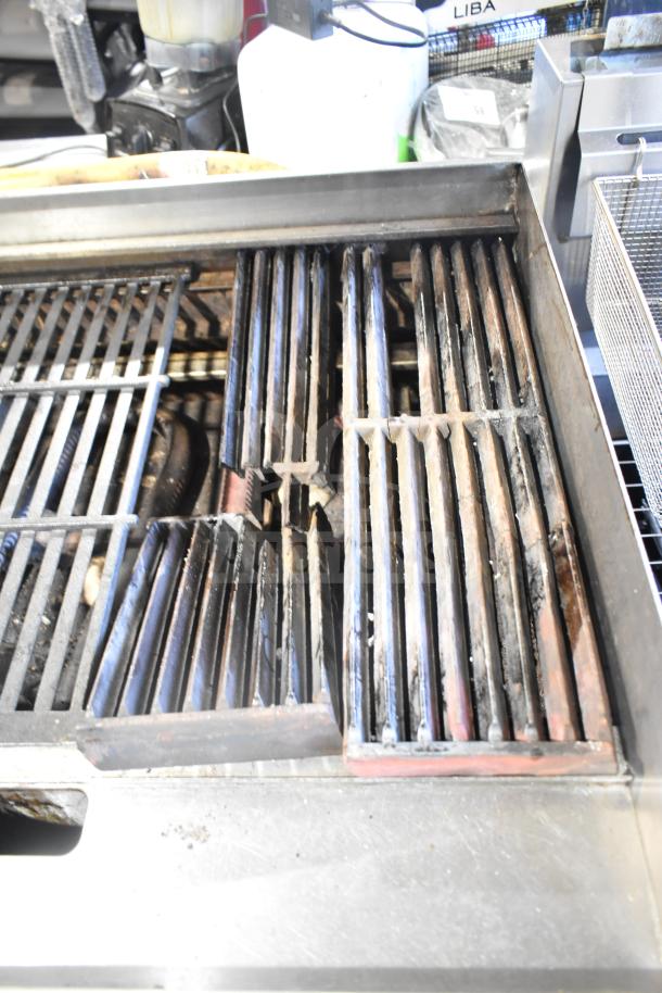Globe commercial countertop gas charbroiler grill on equipment stand with casters, showing used, rusted grates and sturdy construction.
