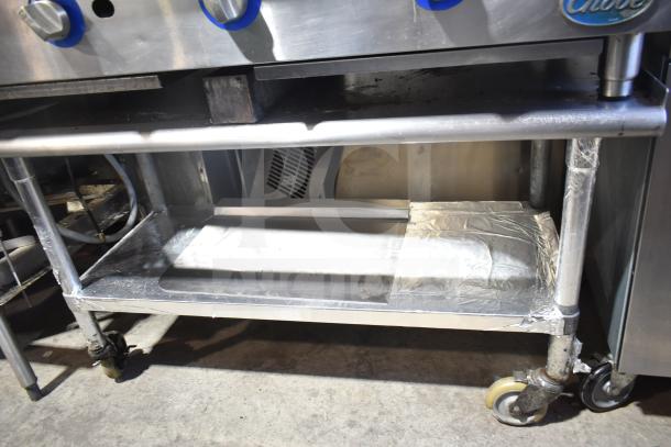 Globe Commercial Gas Charbroiler Grill on castered stand, stainless steel, used, equipped with control knobs, blue accents.