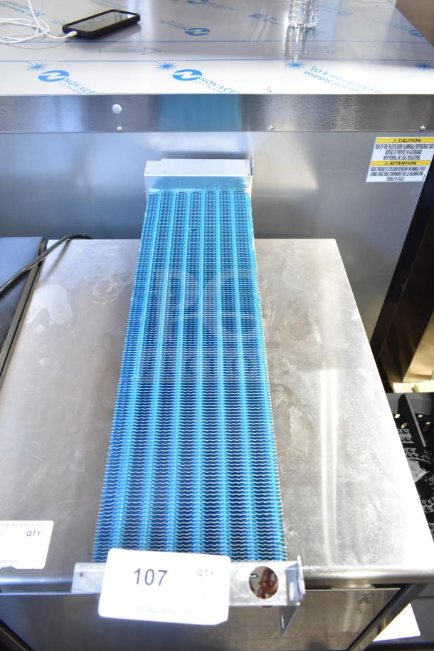 Brand new evaporator coil with blue fins. Slight scratches on metal. Includes safety and model labels. Auction tag "107".