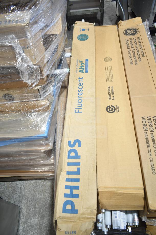 Pallet of 12 scratch and dent Philips fluorescent tube lights in original boxes, visible brand markings and labels.