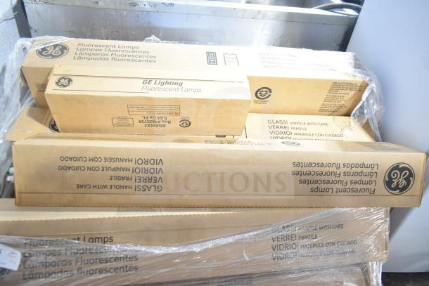 Boxes of brand new GE fluorescent lamps with visible "Handle with Care" labels, some packaging wear.