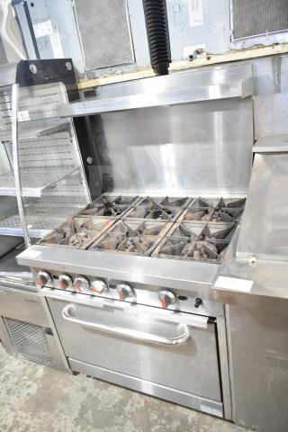 Commercial gas-powered 6 burner range with oven, over shelf, and backsplash in used condition. Stainless steel finish.