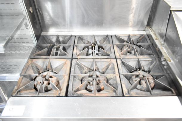 Commercial gas-powered 6 burner range with oven, overshelf, and backsplash. Used condition, stainless steel finish.