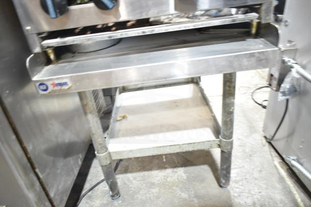 Radiance 4 burner gas range on equipment stand, commercial-grade, visible wear, NSF label, stainless steel construction.