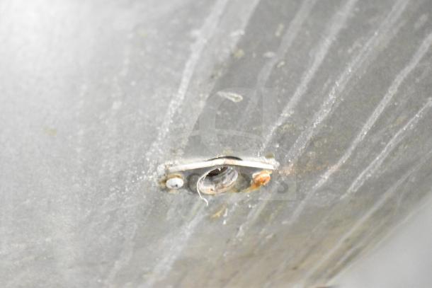 A close-up of a metallic surface on a Manitowoc commercial ice machine, showing slight wear and oxidation around a screw.