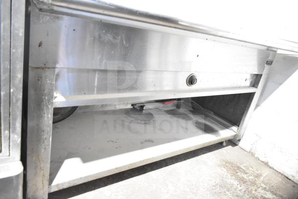 Commercial electric steam table with under shelf, stainless steel, visible wear, ideal for food service.