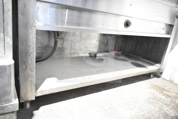 Commercial electric steam table with under shelf, stainless steel, wear shown, ideal for restaurant use.