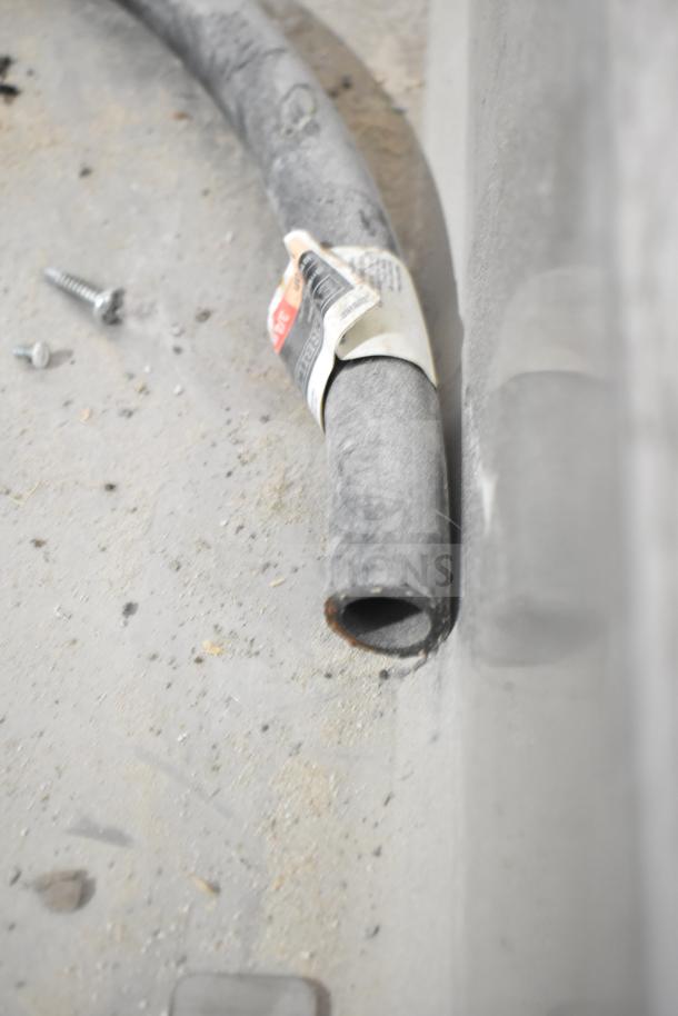 Close-up of a cable with a label attached, lying on a dusty surface near a screw.