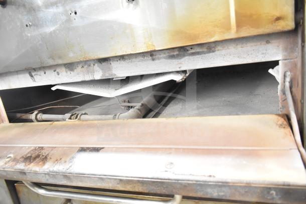 Bakers Pride DS-805 pizza oven interior, showing natural gas components and signs of use. Single deck commercial model.