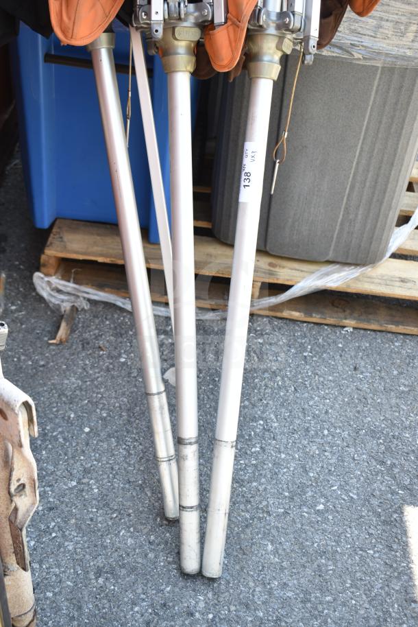 Three patio umbrella poles with metal fixtures, labeled "Asset 138," showing minor wear, auction includes bid multiplier.