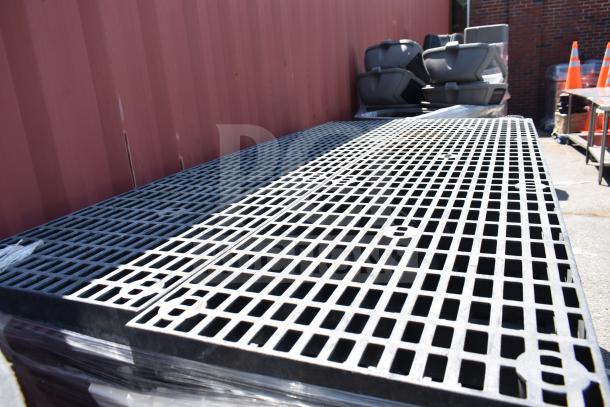 32 black poly shelves with grid design, stacked outdoors. Durable material, good condition. Auctioned at 32 times your bid.