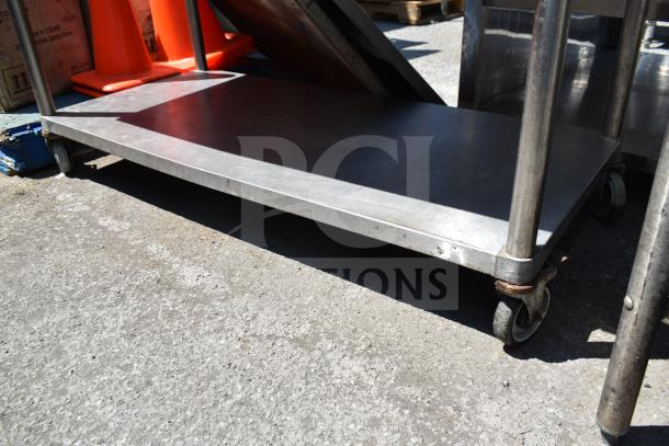 Commercial table with under shelf, stainless steel, mounted on commercial casters, used condition, ideal for kitchens.