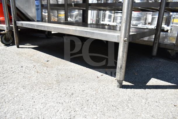 Commercial table with stainless steel construction, features an under shelf and wheels for mobility; used condition.